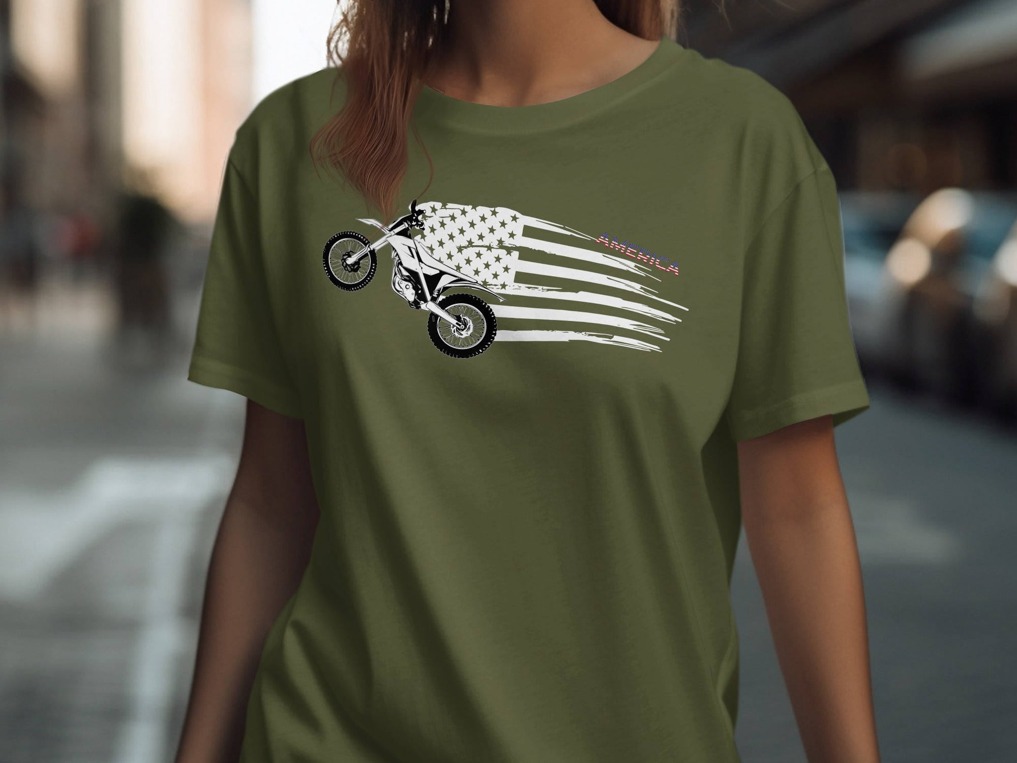 Olive green t-shirt with a dirt bike performing a wheelie with a distressed American flag design.