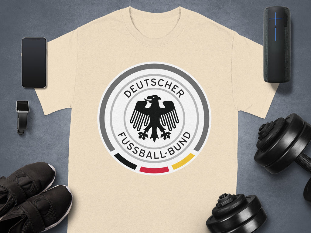 Light tan t-shirt with Deutscher Fußball-Bund logo and athletic accessories.