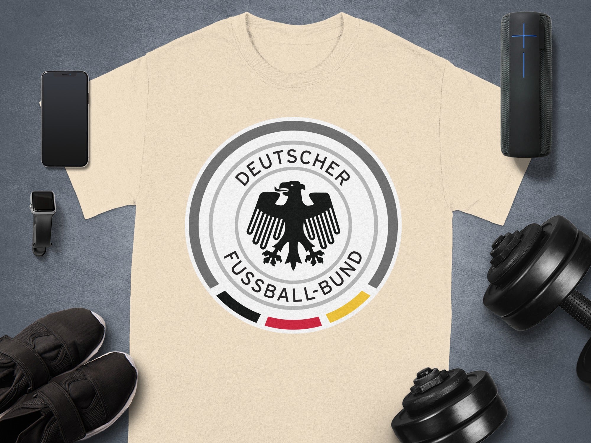 Light tan t-shirt with Deutscher Fußball-Bund logo and athletic accessories.