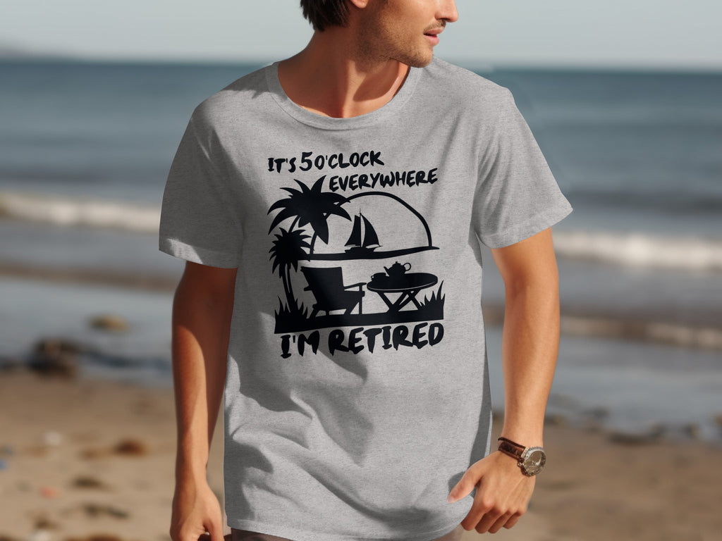 Grey t-shirt with black graphic: "It's 5 O'Clock Everywhere, I'm Retired"